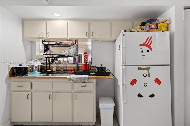 kitchen with sink, white cabinetry, and white refrigerator