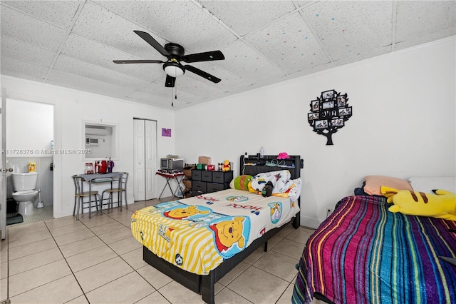 tiled bedroom featuring ceiling fan, a closet, ensuite bath, and a paneled ceiling