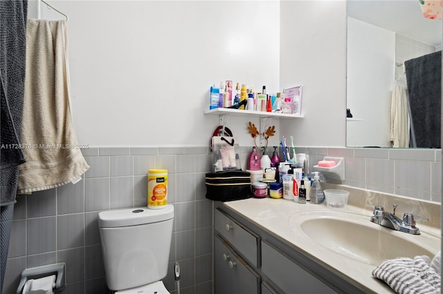 bathroom featuring toilet, tile walls, and vanity