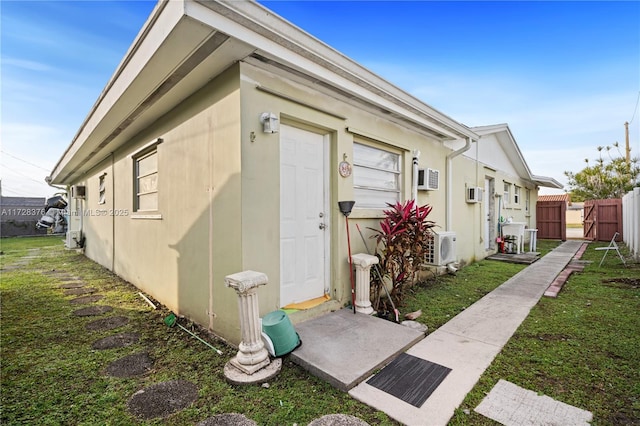 view of outbuilding featuring a lawn, ac unit, and a wall mounted air conditioner