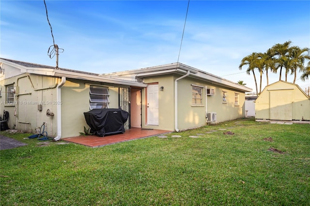 rear view of house featuring a lawn, a storage unit, and a patio