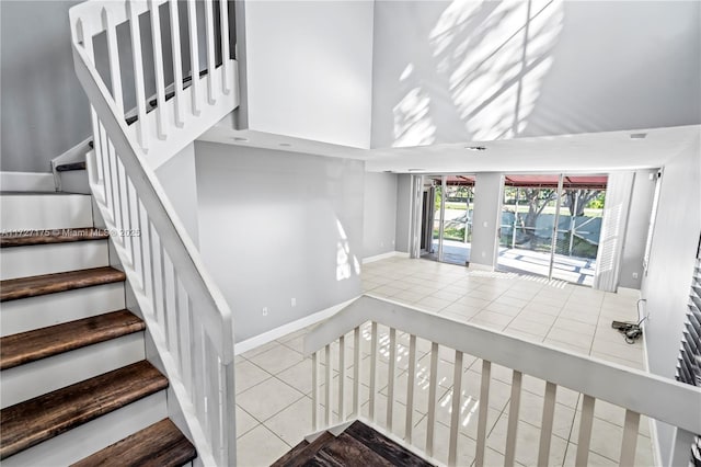 stairs featuring a towering ceiling and tile patterned flooring