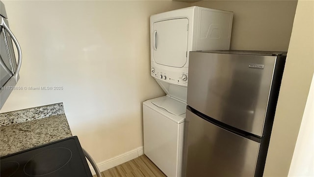 washroom with stacked washer / dryer and light wood-type flooring