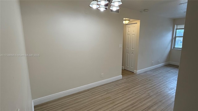 spare room with a textured ceiling, a notable chandelier, and light wood-type flooring