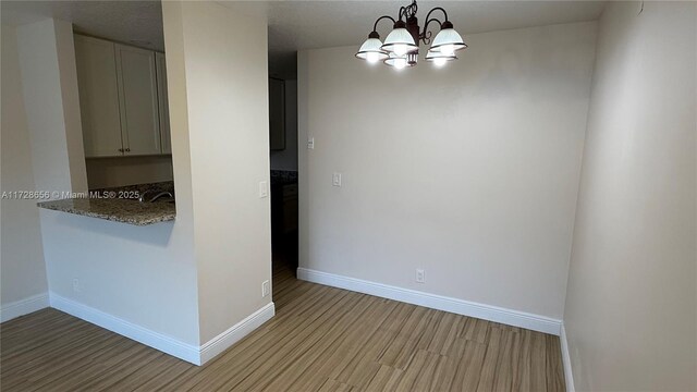 unfurnished room featuring an inviting chandelier and light hardwood / wood-style floors