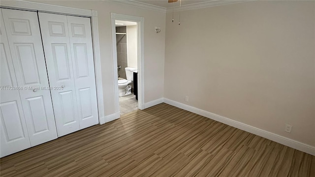 unfurnished bedroom featuring a closet, ornamental molding, and hardwood / wood-style flooring