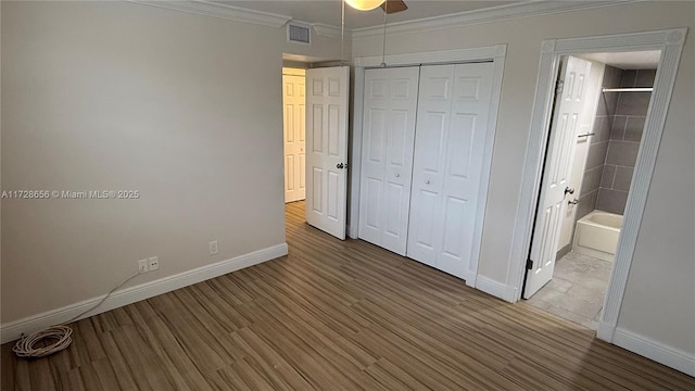 unfurnished bedroom with ceiling fan, crown molding, and wood-type flooring