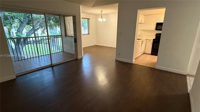 empty room featuring light hardwood / wood-style flooring, a chandelier, and a healthy amount of sunlight