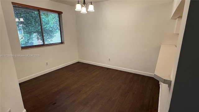 spare room with dark hardwood / wood-style flooring and a notable chandelier