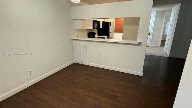 kitchen featuring white cabinetry, kitchen peninsula, fridge, dark hardwood / wood-style flooring, and electric range oven