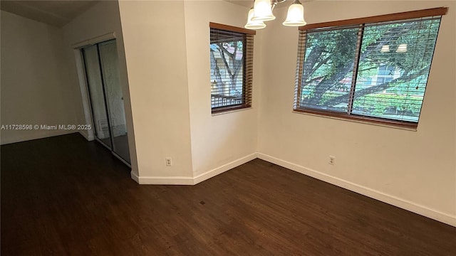 unfurnished room featuring dark wood-type flooring, lofted ceiling, and a notable chandelier