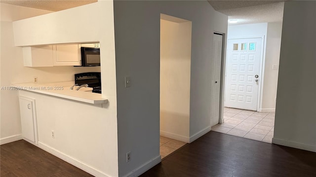 interior space with light wood-type flooring, a textured ceiling, white cabinetry, and range