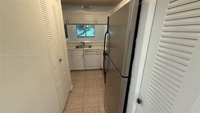 kitchen featuring light tile patterned floors, stainless steel fridge, sink, and white dishwasher