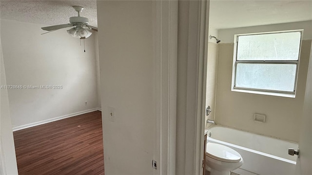 bathroom featuring toilet, shower / bath combination, ceiling fan, wood-type flooring, and a textured ceiling