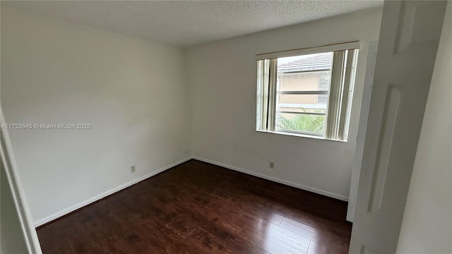 empty room featuring dark hardwood / wood-style floors and a textured ceiling