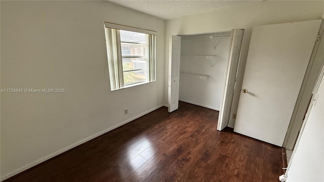 unfurnished bedroom featuring a closet, dark hardwood / wood-style flooring, and a textured ceiling