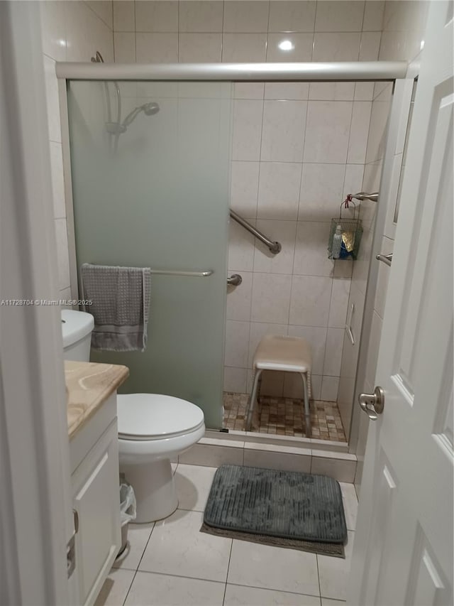 bathroom with toilet, vanity, tile walls, tile patterned floors, and a shower with door