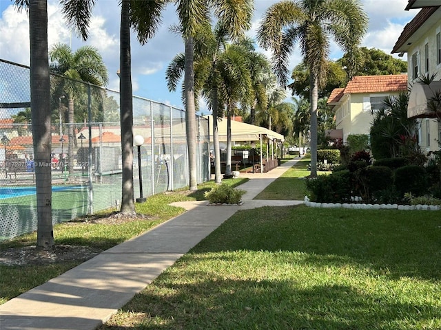 view of community featuring tennis court and a lawn