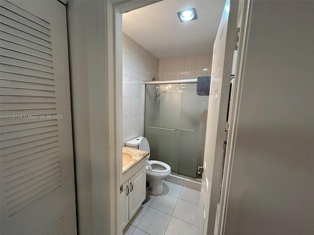 bathroom with vanity, toilet, a shower with door, and tile patterned flooring