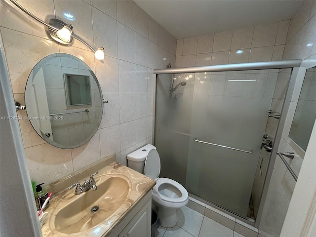 bathroom featuring tile patterned flooring, tile walls, vanity, a shower with shower door, and toilet