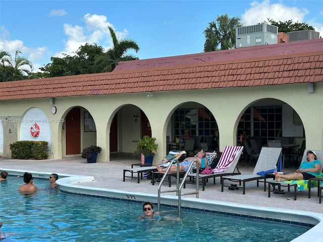 rear view of property with a patio area, cooling unit, and a community pool