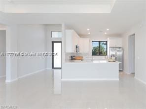 kitchen with kitchen peninsula, stainless steel refrigerator with ice dispenser, and white cabinetry