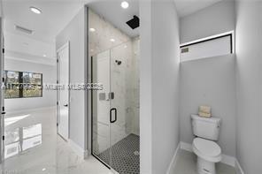 bathroom with a shower with shower door and toilet