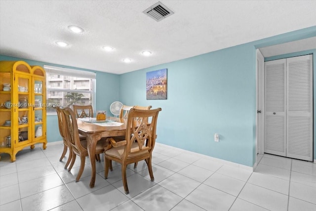 dining area with a textured ceiling and light tile patterned floors