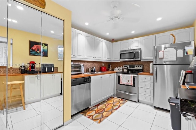 kitchen with white cabinets, appliances with stainless steel finishes, sink, backsplash, and light tile patterned floors