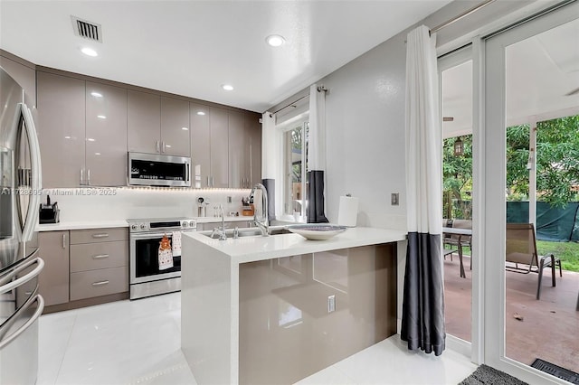 kitchen with gray cabinetry, sink, stainless steel appliances, and kitchen peninsula