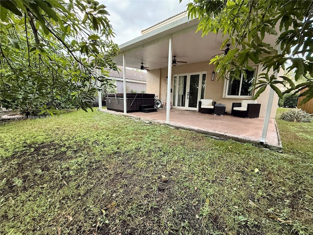 view of yard with a hot tub, a patio, ceiling fan, and french doors