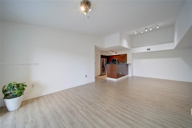 unfurnished living room with light hardwood / wood-style flooring and a towering ceiling