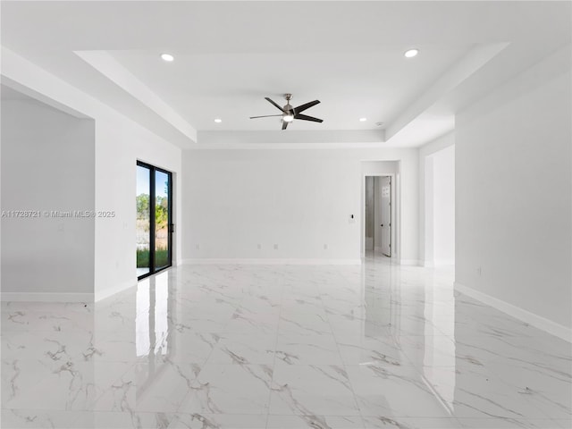 empty room featuring ceiling fan and a raised ceiling