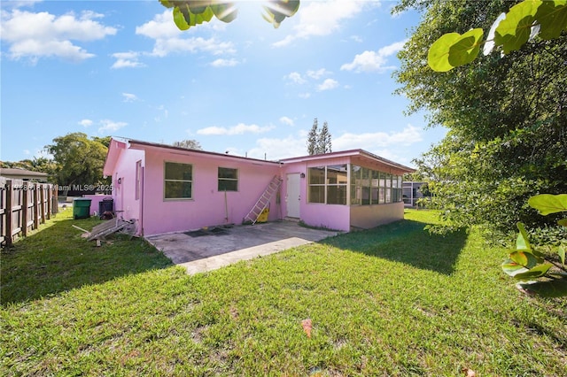 back of property featuring a yard, a patio area, and a sunroom