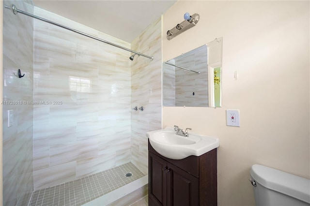 bathroom featuring vanity, toilet, and tiled shower