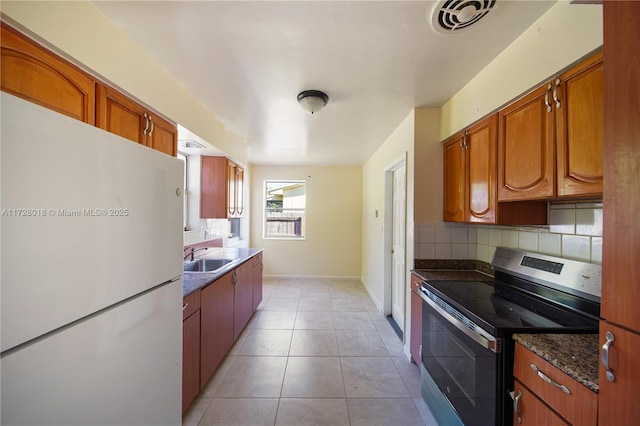 kitchen with light tile patterned flooring, sink, decorative backsplash, white refrigerator, and stainless steel electric range