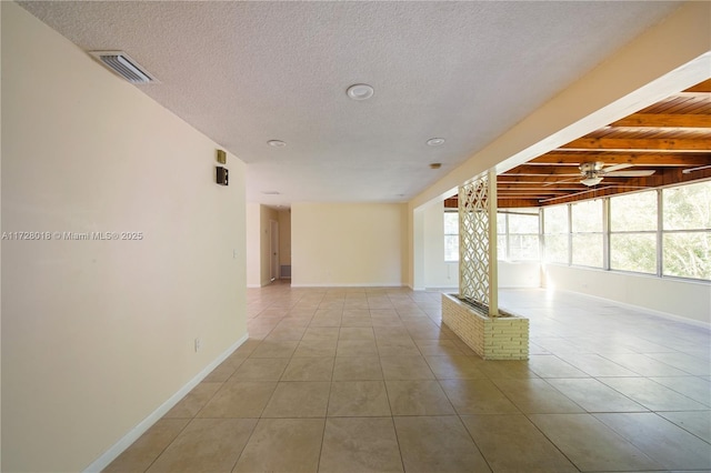 empty room with light tile patterned flooring, ceiling fan, and beam ceiling