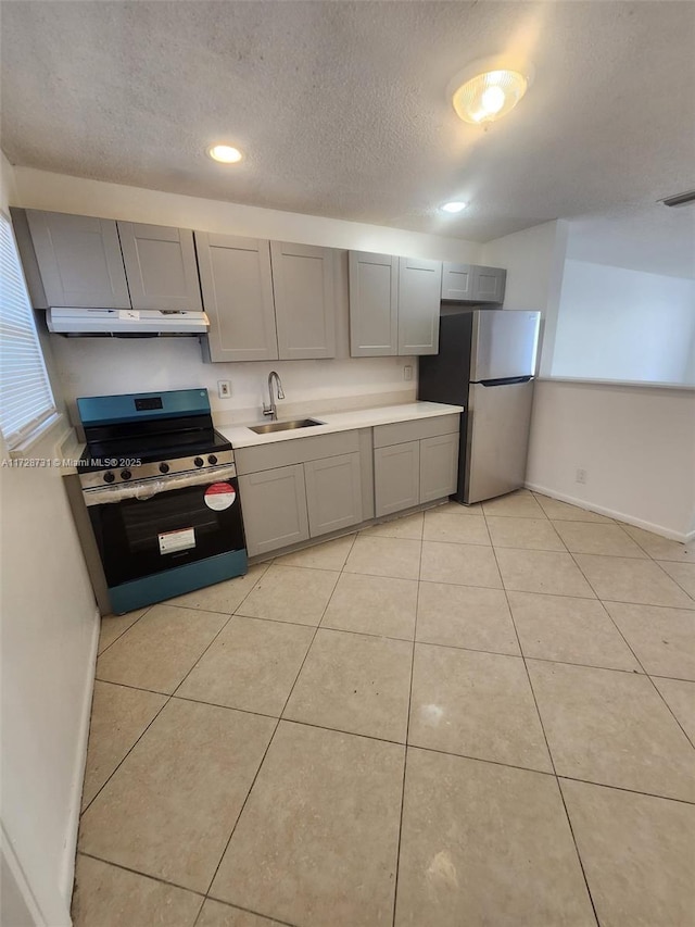 kitchen with a textured ceiling, appliances with stainless steel finishes, sink, light tile patterned floors, and gray cabinetry