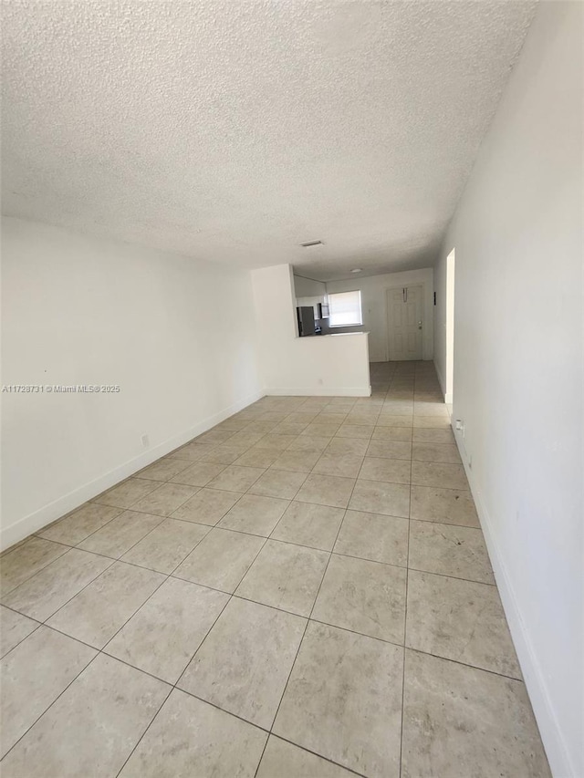 spare room with a textured ceiling and light tile patterned floors