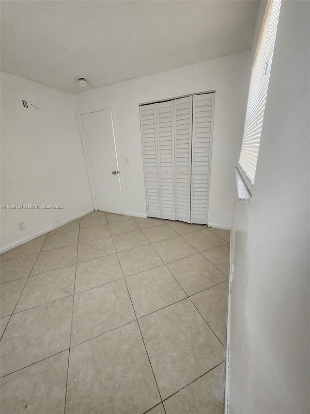 unfurnished bedroom with a closet and light tile patterned flooring