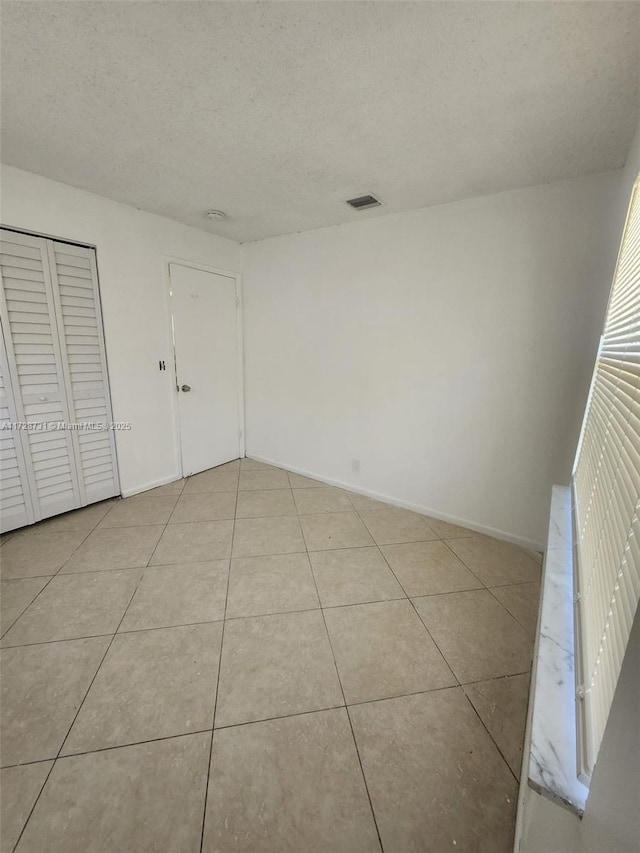 unfurnished bedroom with a closet, light tile patterned flooring, and a textured ceiling