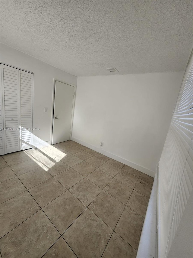 tiled spare room featuring a textured ceiling