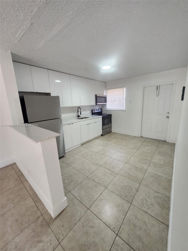 kitchen featuring a textured ceiling, white cabinetry, stainless steel appliances, sink, and light tile patterned floors