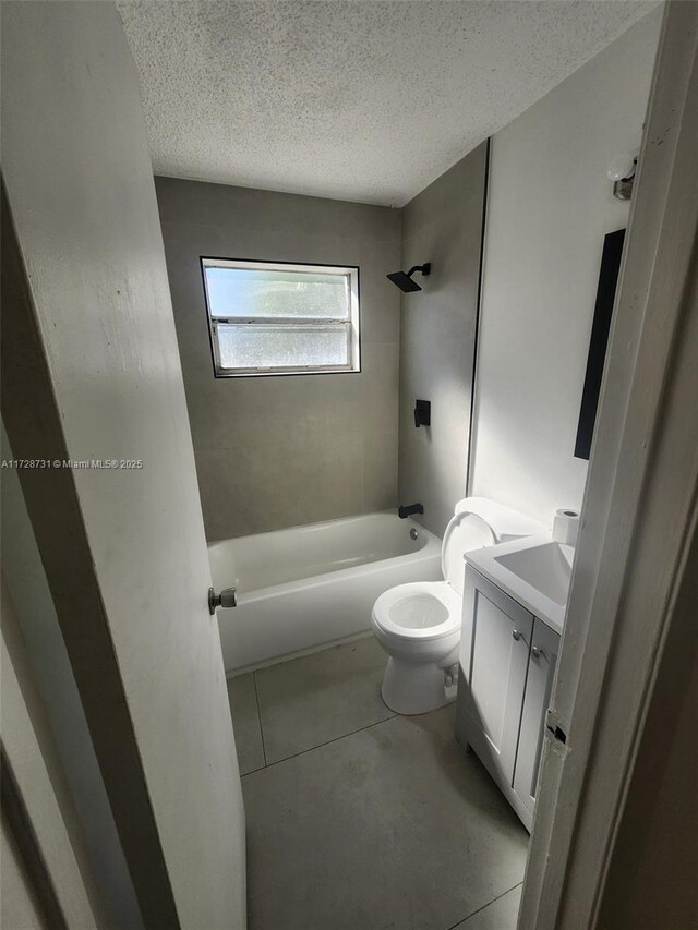 full bathroom featuring a textured ceiling, toilet, tiled shower / bath, and vanity