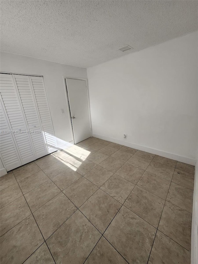 unfurnished bedroom with light tile patterned floors, a closet, and a textured ceiling