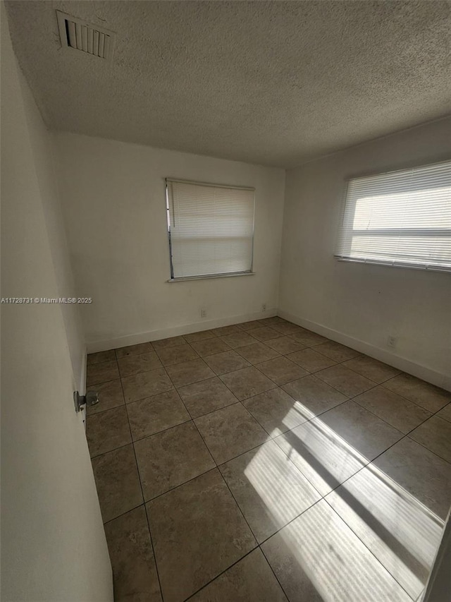 tiled spare room featuring a textured ceiling