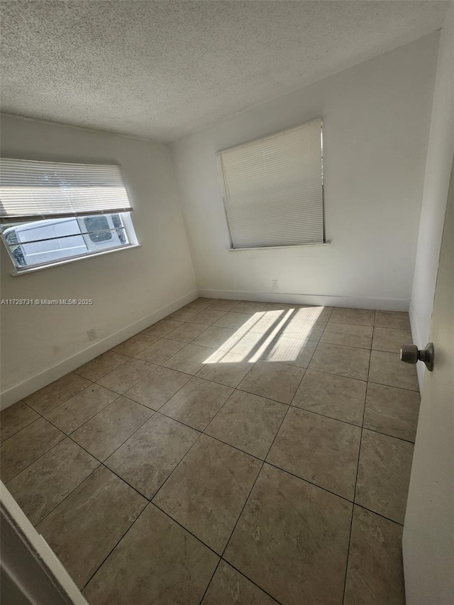 tiled spare room with a textured ceiling