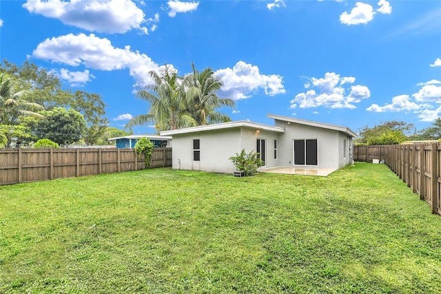 rear view of property featuring a lawn and a patio