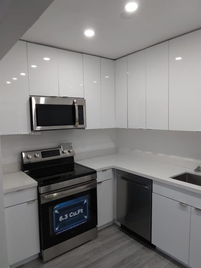 kitchen featuring hardwood / wood-style flooring, stainless steel appliances, and white cabinetry