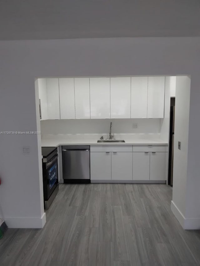 kitchen with sink, white cabinetry, appliances with stainless steel finishes, and light wood-type flooring